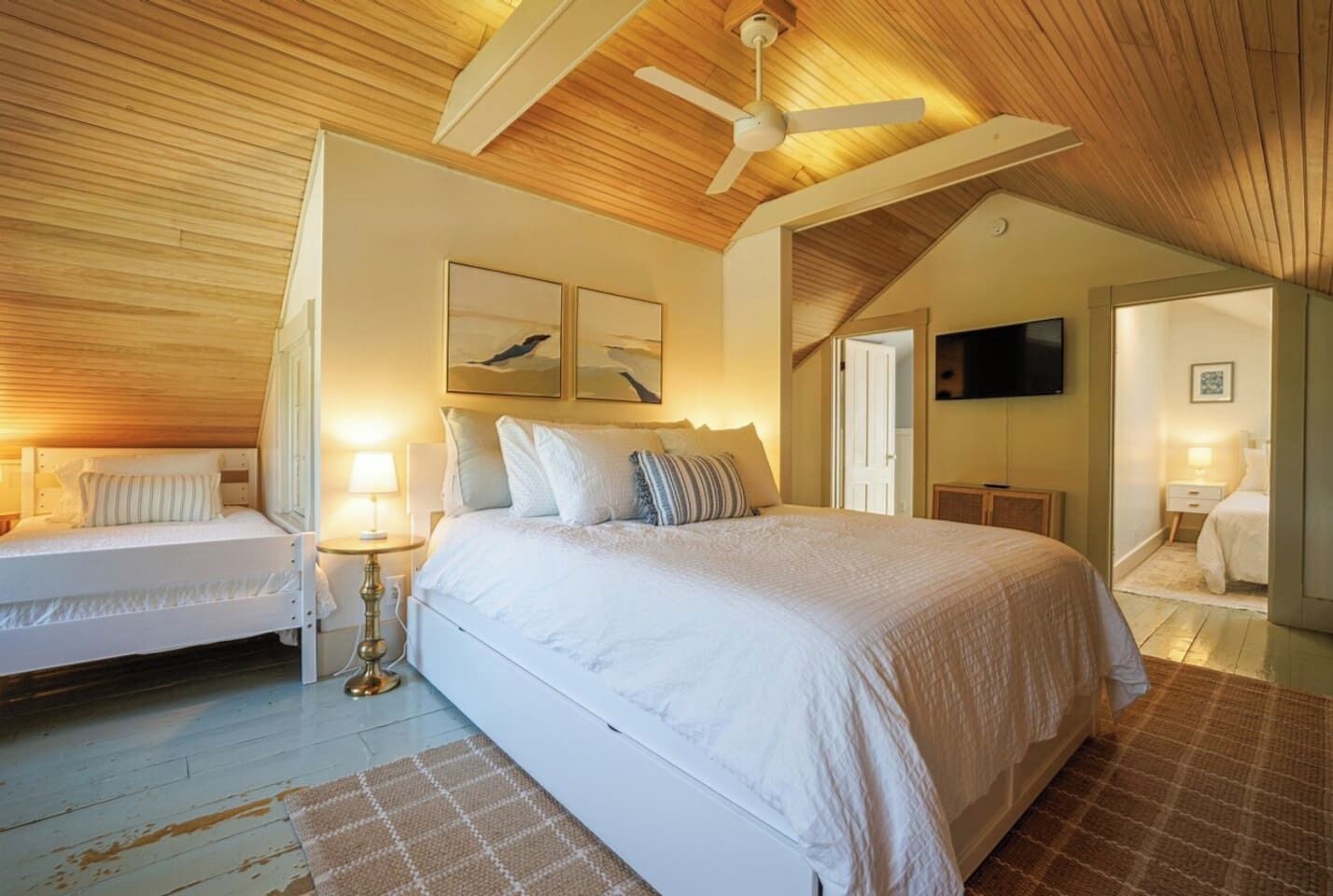 A bedroom with a bed, bedside tables, a ceiling fan, and a television.