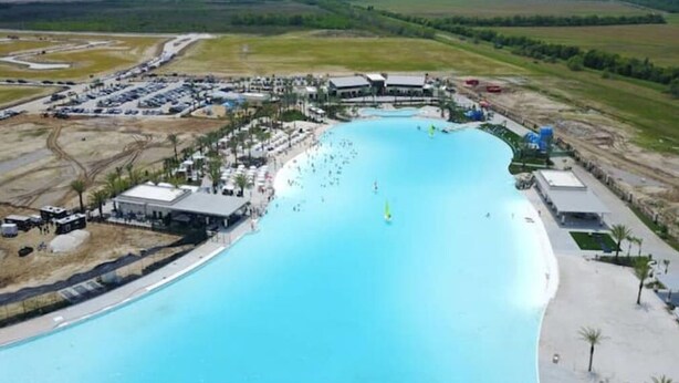 An aerial view of a resort with a large swimming pool, multiple buildings, and a parking area. - Cozy Duplex Close to Hobby, Lagoon, NASA, Beaches! (Pasadena)