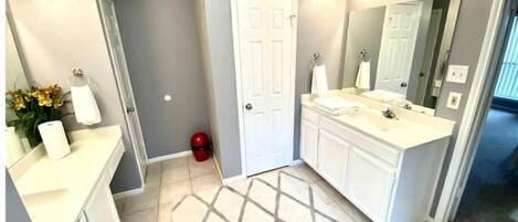 A bathroom with a vanity, a large mirror, and a lighted vanity area.