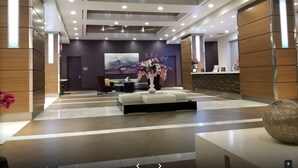En moderne lobby med receptionsdisk, siddeområde og et stort abstrakt maleri på væggen.