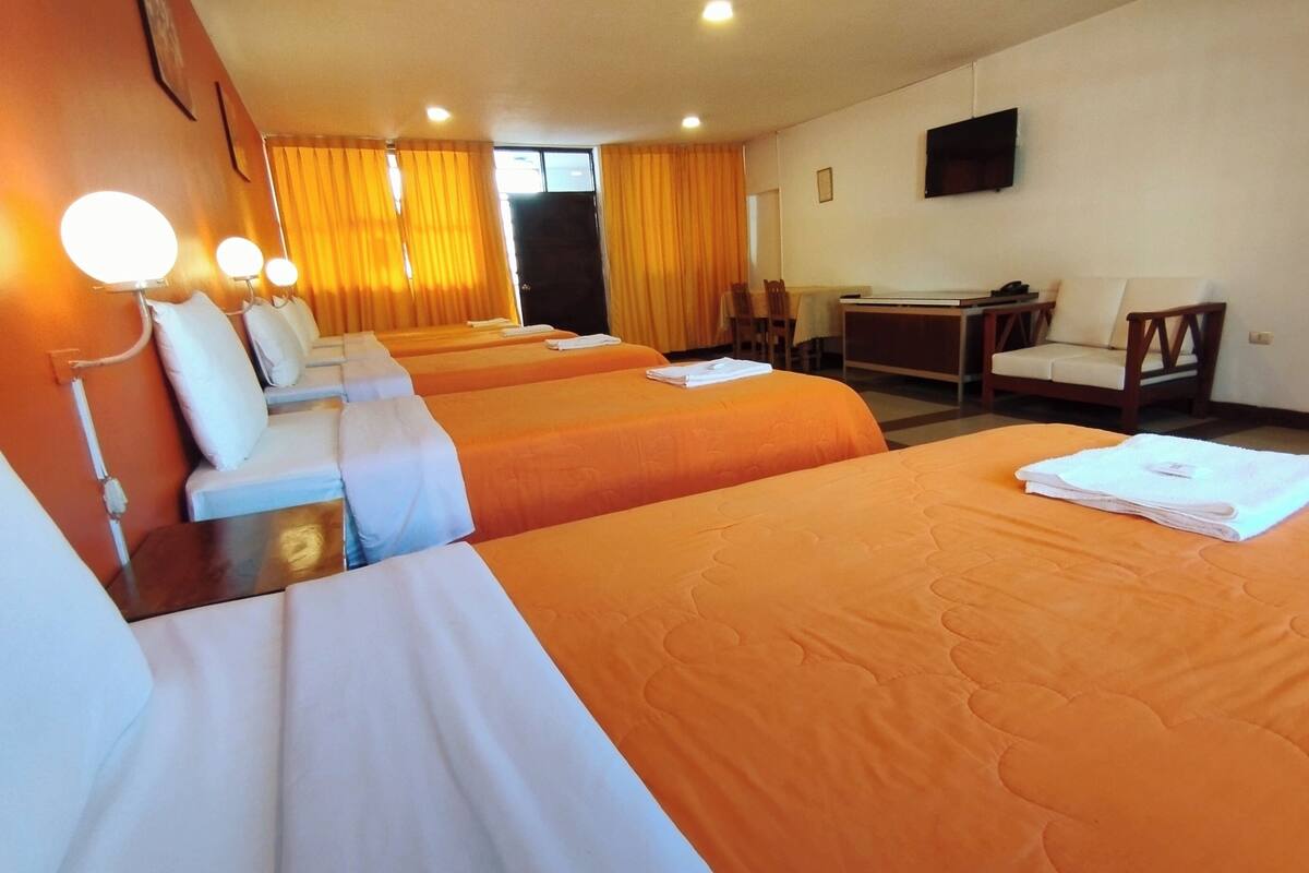 Ein Hotelzimmer mit zwei Betten, einem Schreibtisch, einem Stuhl und einem an der Wand befestigten Fernseher.