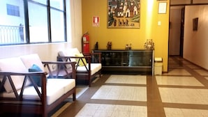 Un área de recepción con dos sillas de madera, un expositor de vidrio y un cuadro en la pared.