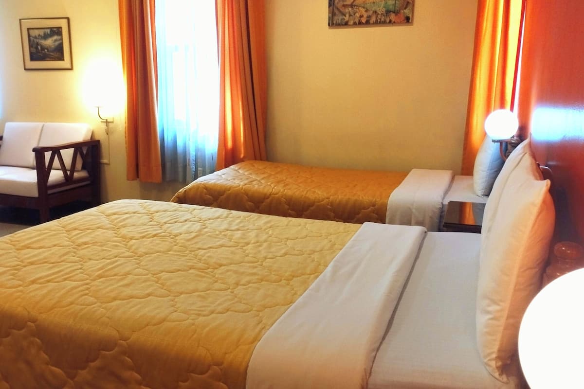 Ein Hotelzimmer mit zwei Betten, einem Sessel und einem Nachttisch.
