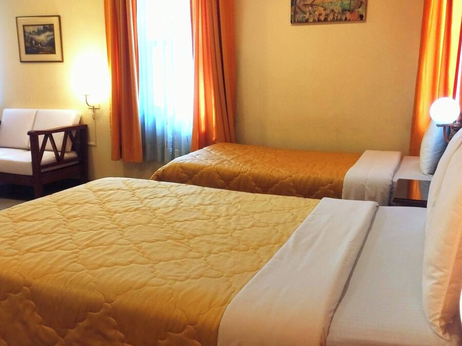 A hotel room with two beds, a chair, and a nightstand.