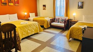 Una habitación de hotel con dos camas, un sofá, un escritorio y obras de arte en las paredes.