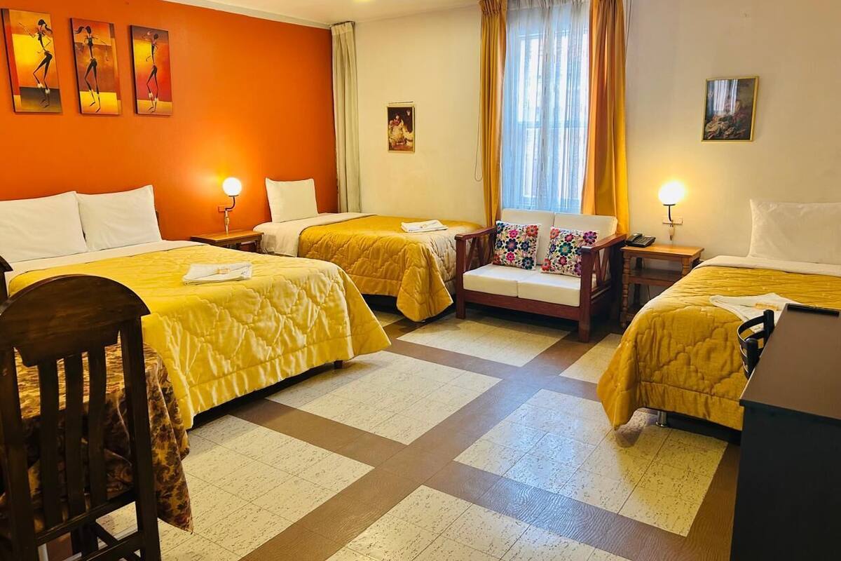 Ein Hotelzimmer mit zwei Betten, einer Sitzecke, einem Schreibtisch und Bildern an den Wänden.