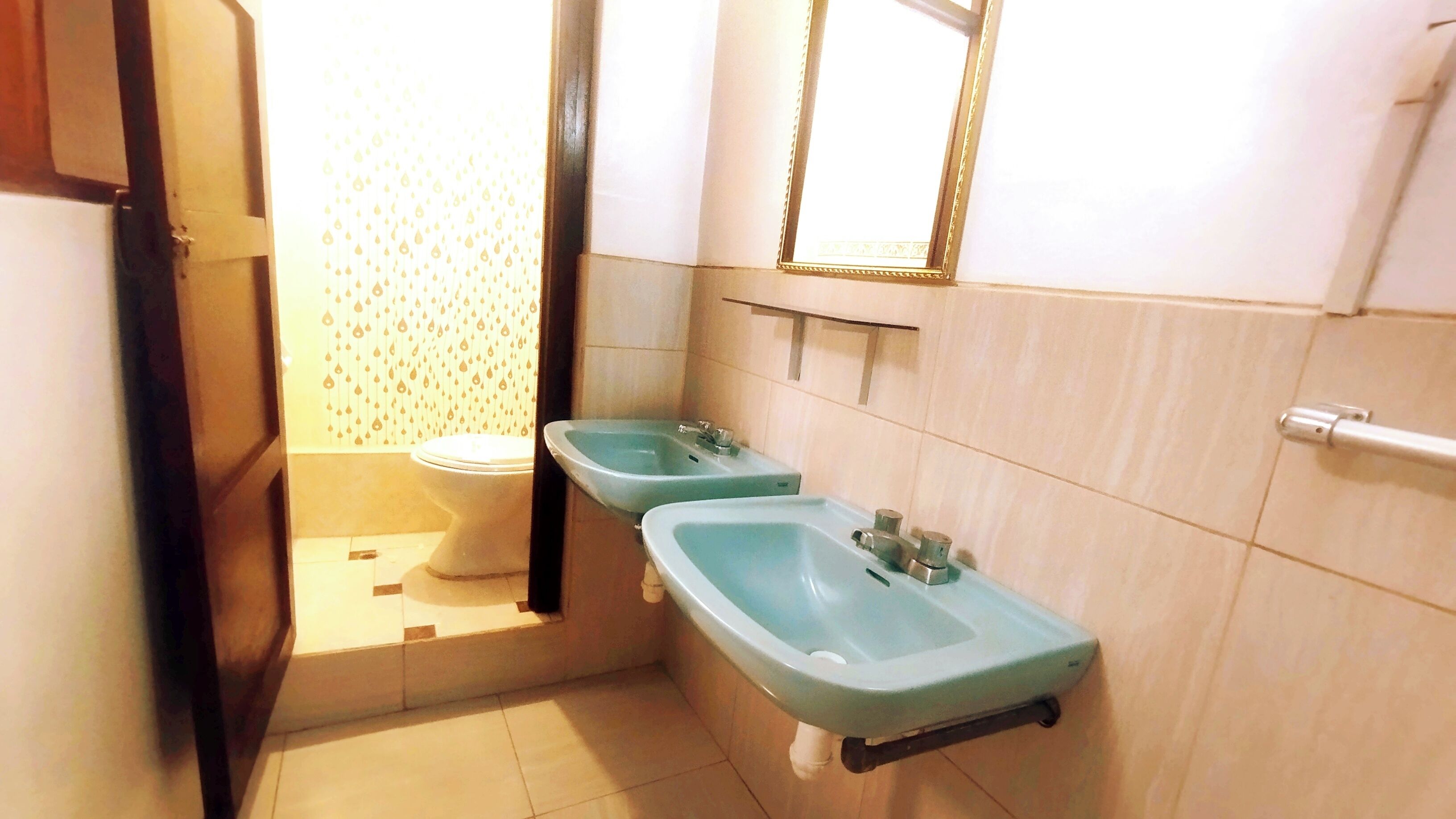 Une salle de bain comprenant des toilettes, deux lavabos, un miroir et un porte-serviettes.