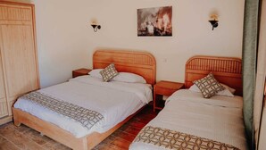 A bedroom with two wooden beds, a wooden wardrobe, a painting of a ship on fire, and wall-mounted lights. - Tunis Pyramids Hotel (Yusuf as-Sidiq)