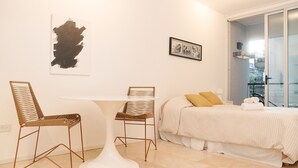 A modern bedroom with a bed, two chairs, a small table, and a large abstract painting on the wall. - Silencioso Studio en Palermo Hollywood (Buenos Aires)