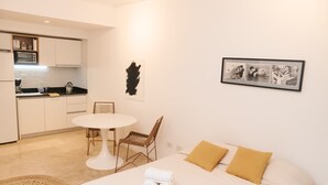 A hotel room with a bed, a small table, a chair, a kitchen area, and a framed picture on the wall. - Silencioso Studio en Palermo Hollywood (Buenos Aires)
