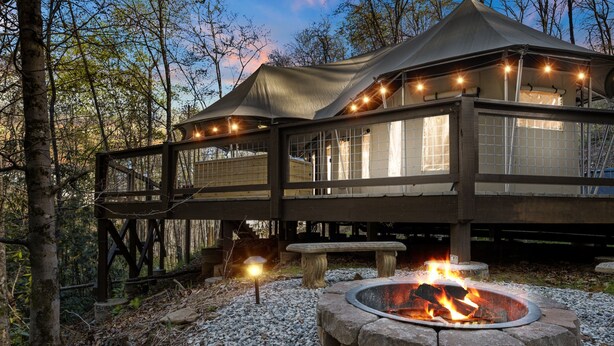 A cabin with a fire pit, wooden deck, and string lights.