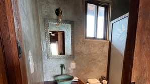A bathroom with a rustic design, featuring a wooden vanity, a white toilet, and a small window. - Krak-Inn Holbox Self Check In (Isla Holbox)