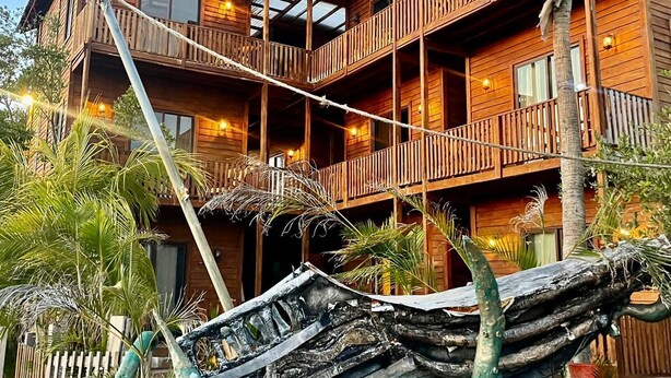 A multi-story wooden building with balconies, a rope bridge, and a wooden boat structure in the foreground. - Krak-Inn Holbox Self Check In (Isla Holbox)