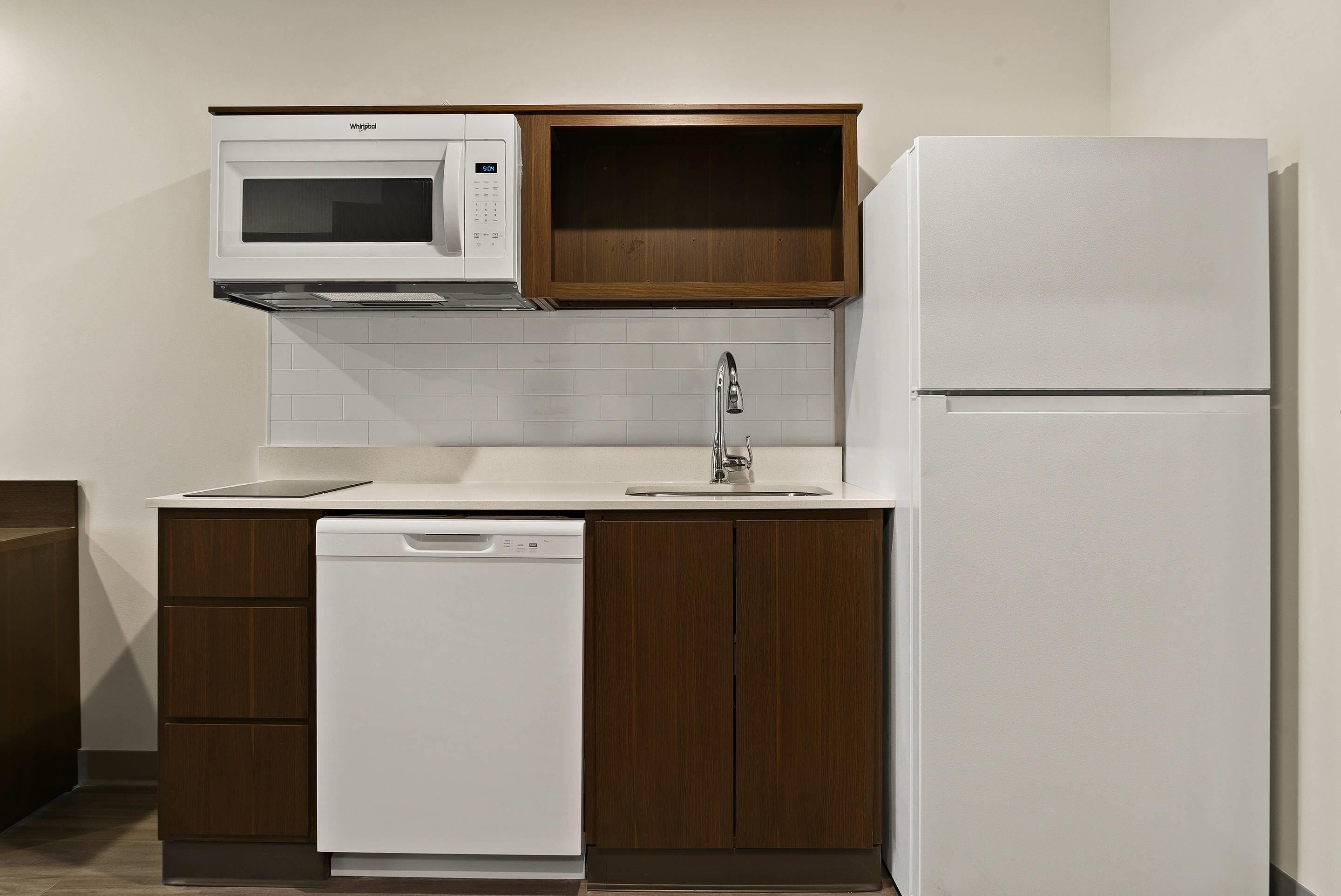 A compact kitchen with a built-in microwave, a dishwasher, and a refrigerator.