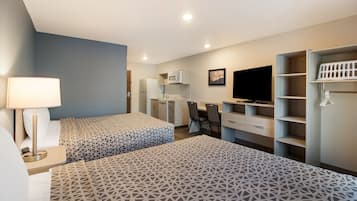 Een hotelkamer met twee bedden, een bureau, een stoel, een televisie en inbouwopslag.