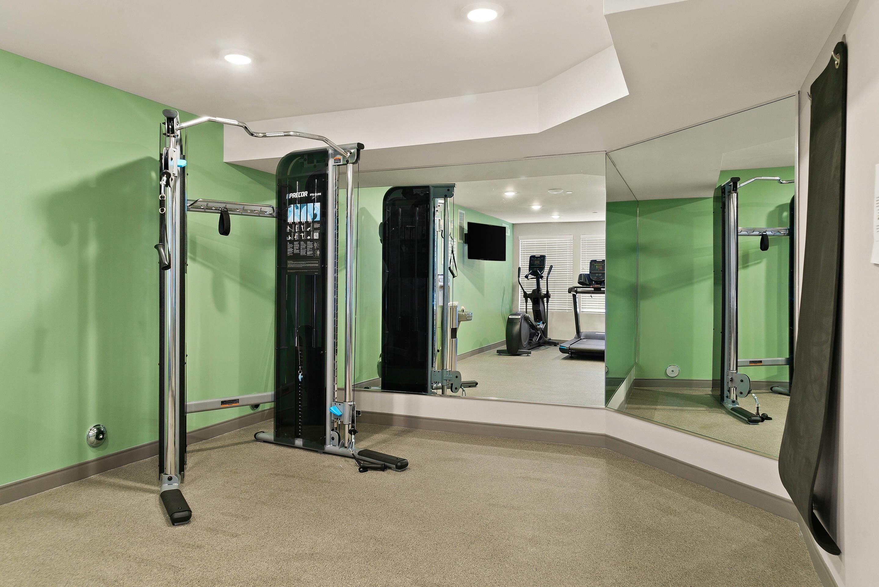 A gym with a pull-up bar, a weight bench, and a mirror.
