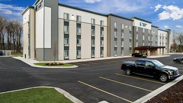 A modern hotel with a parking lot, a covered entrance, and a well-maintained lawn.