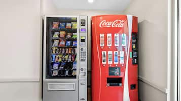 Zwei Getränkeautomaten, einer mit verschiedenen Snacks und der andere mit Getränken, darunter Coca-Cola.