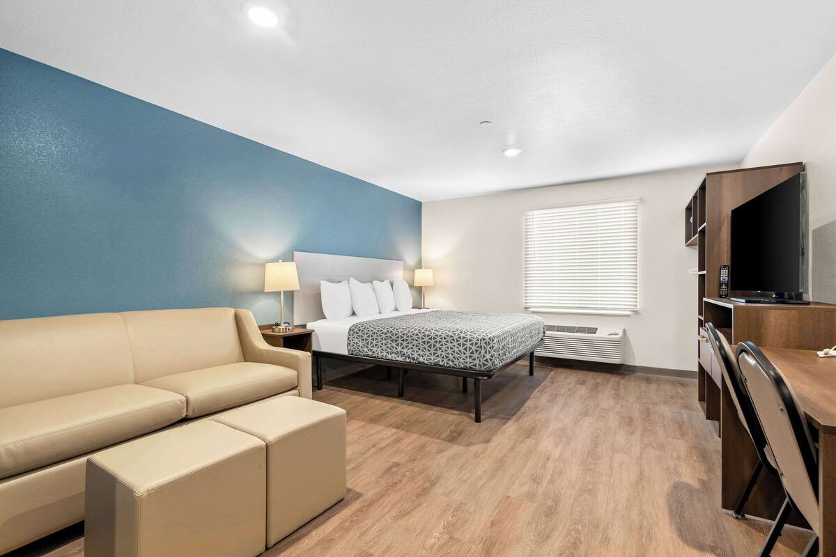 A hotel room with a bed, a sofa, a desk, and a TV.