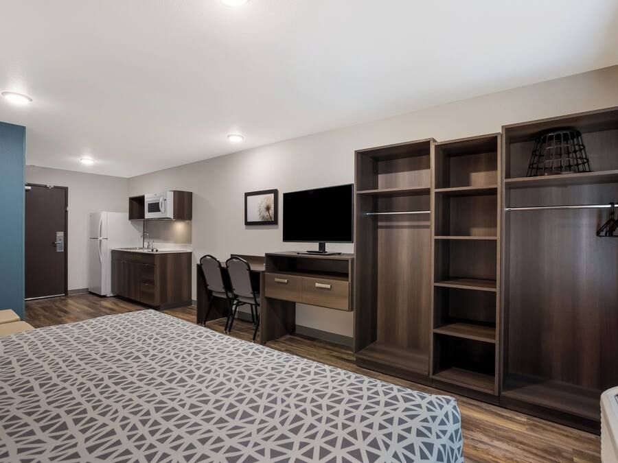 A modern bedroom with a bed, a desk, a TV, and built-in wardrobes.