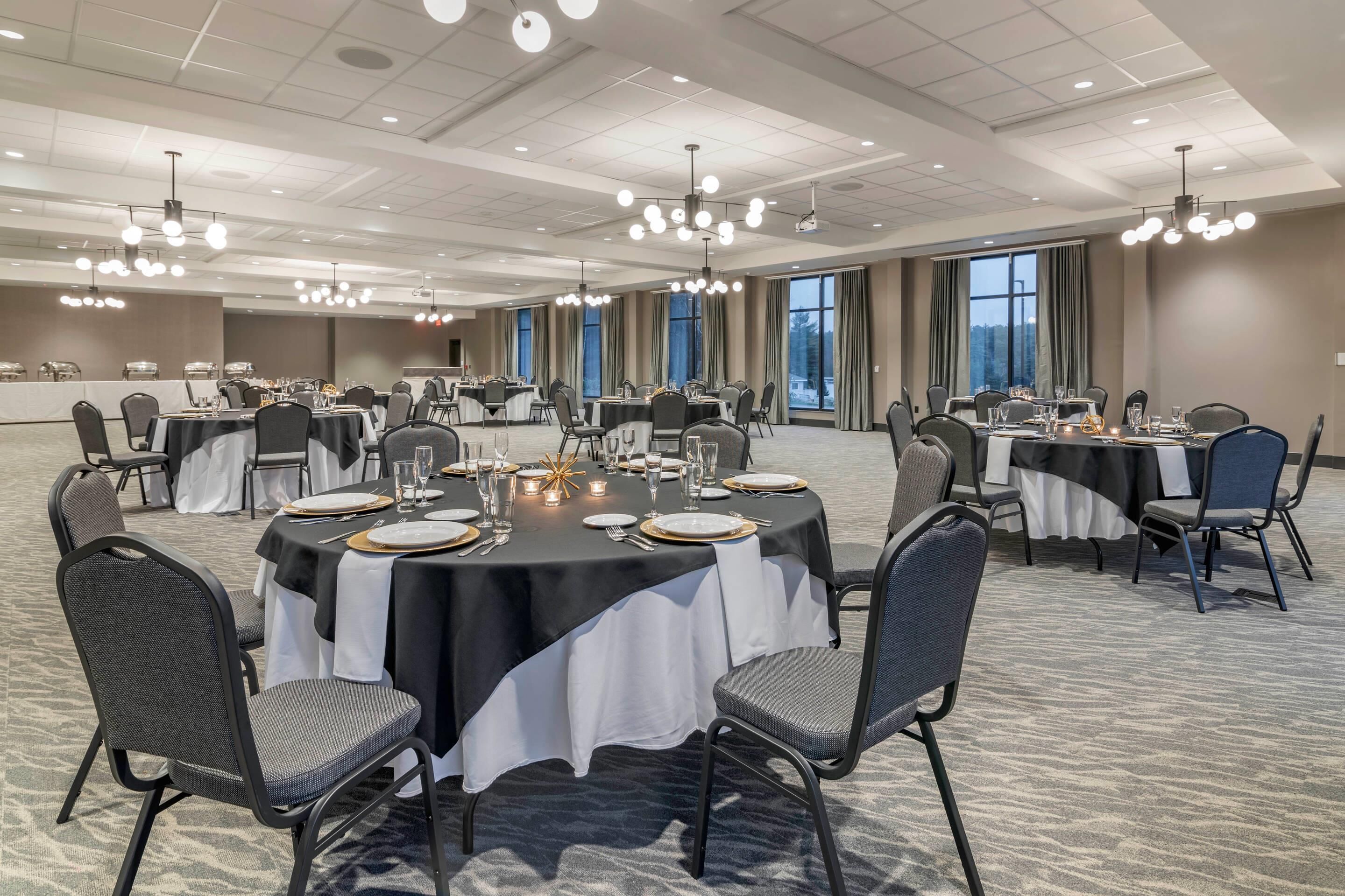 A conference room with round tables, chairs, and a buffet setup.