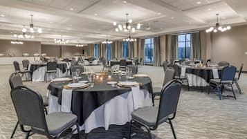 A conference room with round tables, chairs, and a buffet setup.