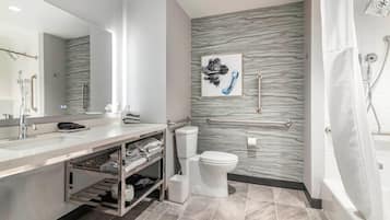 A modern bathroom with a marble backsplash, a toilet, a sink with a vanity, and a shower area.