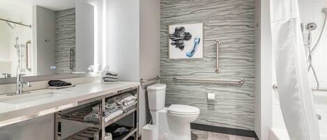 A modern bathroom with a marble backsplash, a toilet, a sink with a vanity, and a shower area.