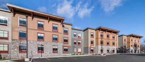 A multi-story residential building with a parking lot in front.