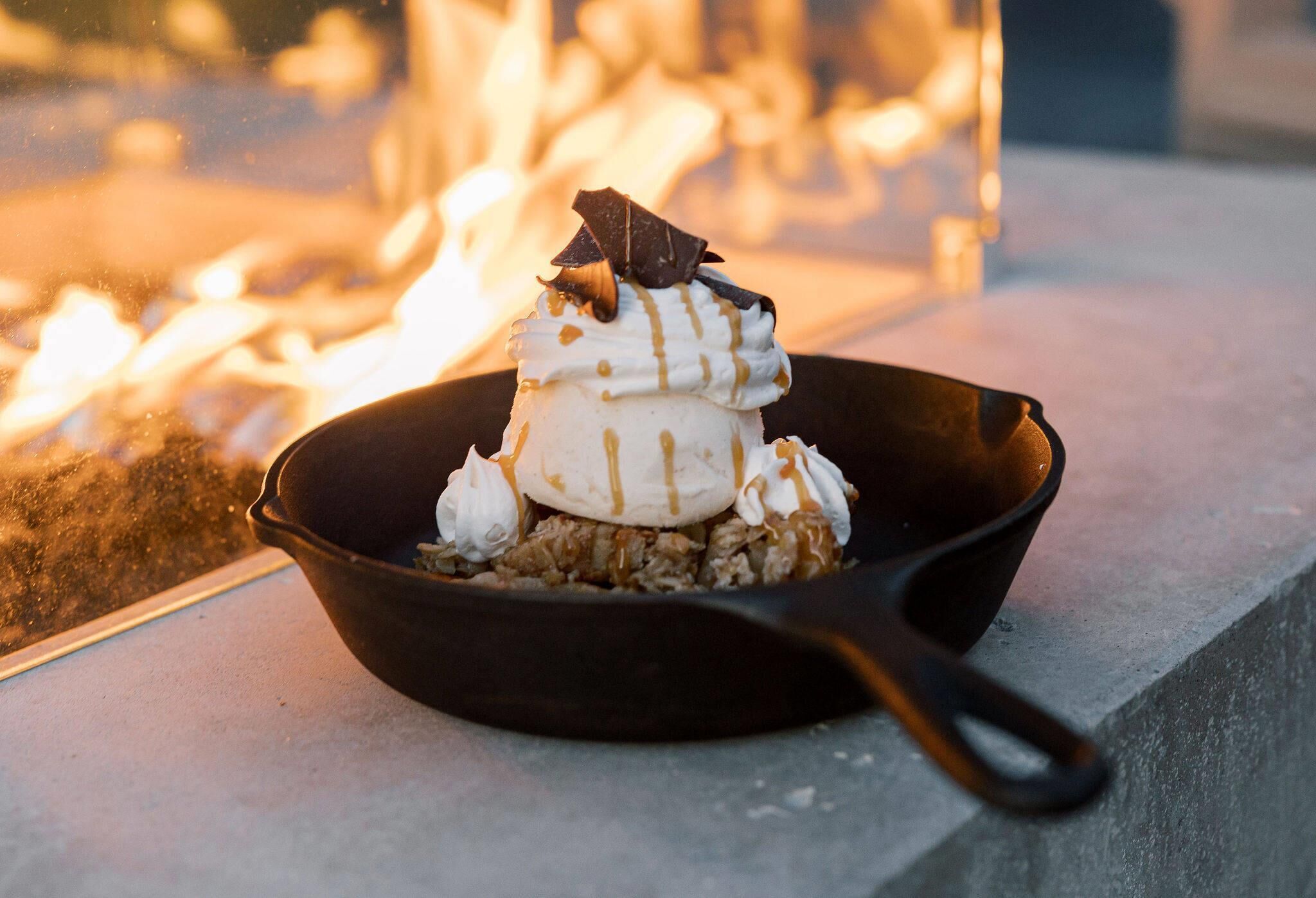 Un postre en una sartén sobre una mesa cerca del fuego.