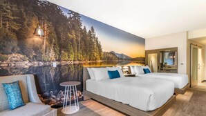 Un dormitorio con cama, sofá, una mesita redonda y un amplio mural en la pared que muestra un bosque y un lago.
