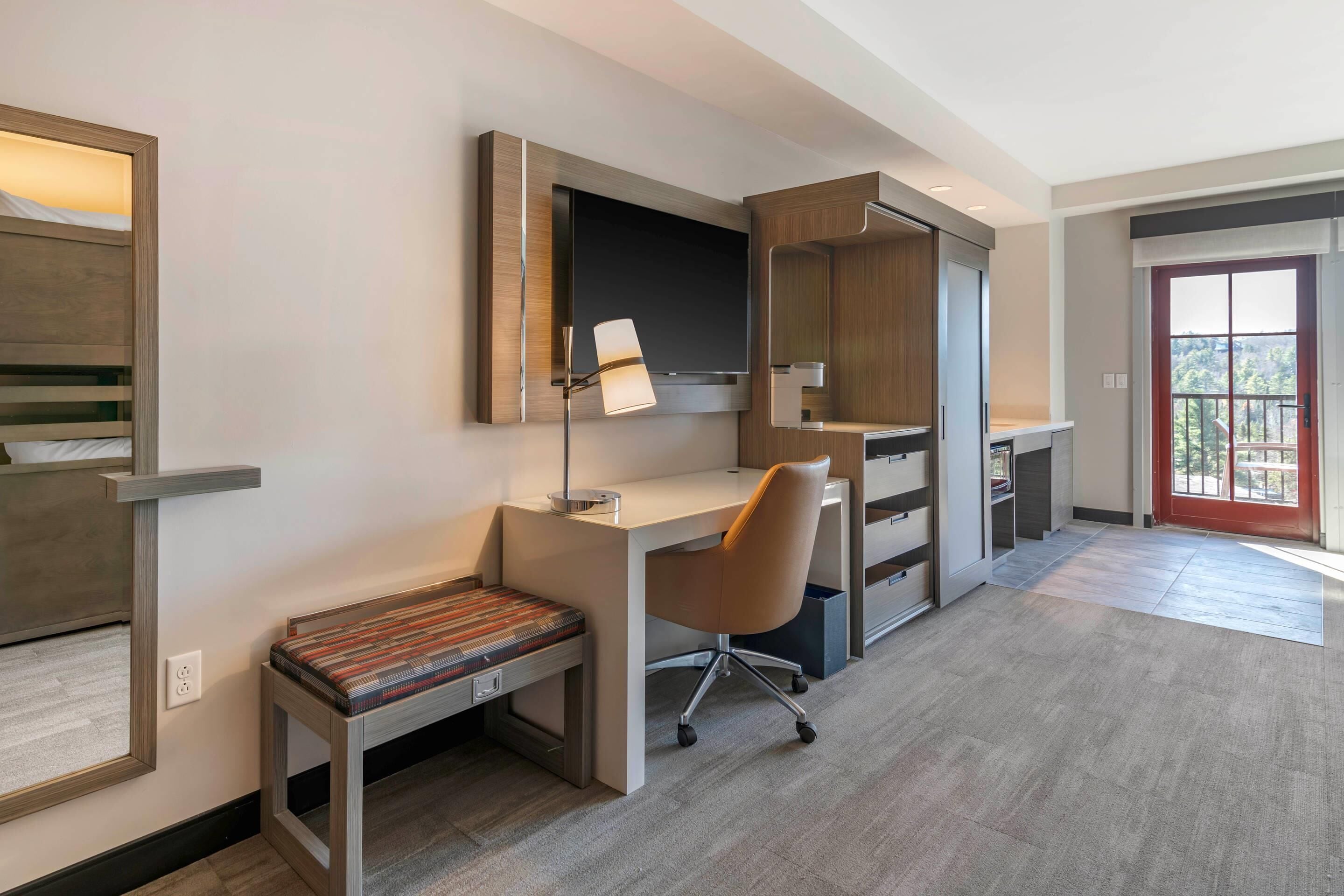 Una habitación de hotel moderna con escritorio, silla y banco.