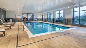 An indoor swimming pool with clear water, wooden flooring, and large windows offering views of the outdoors. - Cambria Hotel Lake Placid - Lakeside Resort (Lake Placid)
