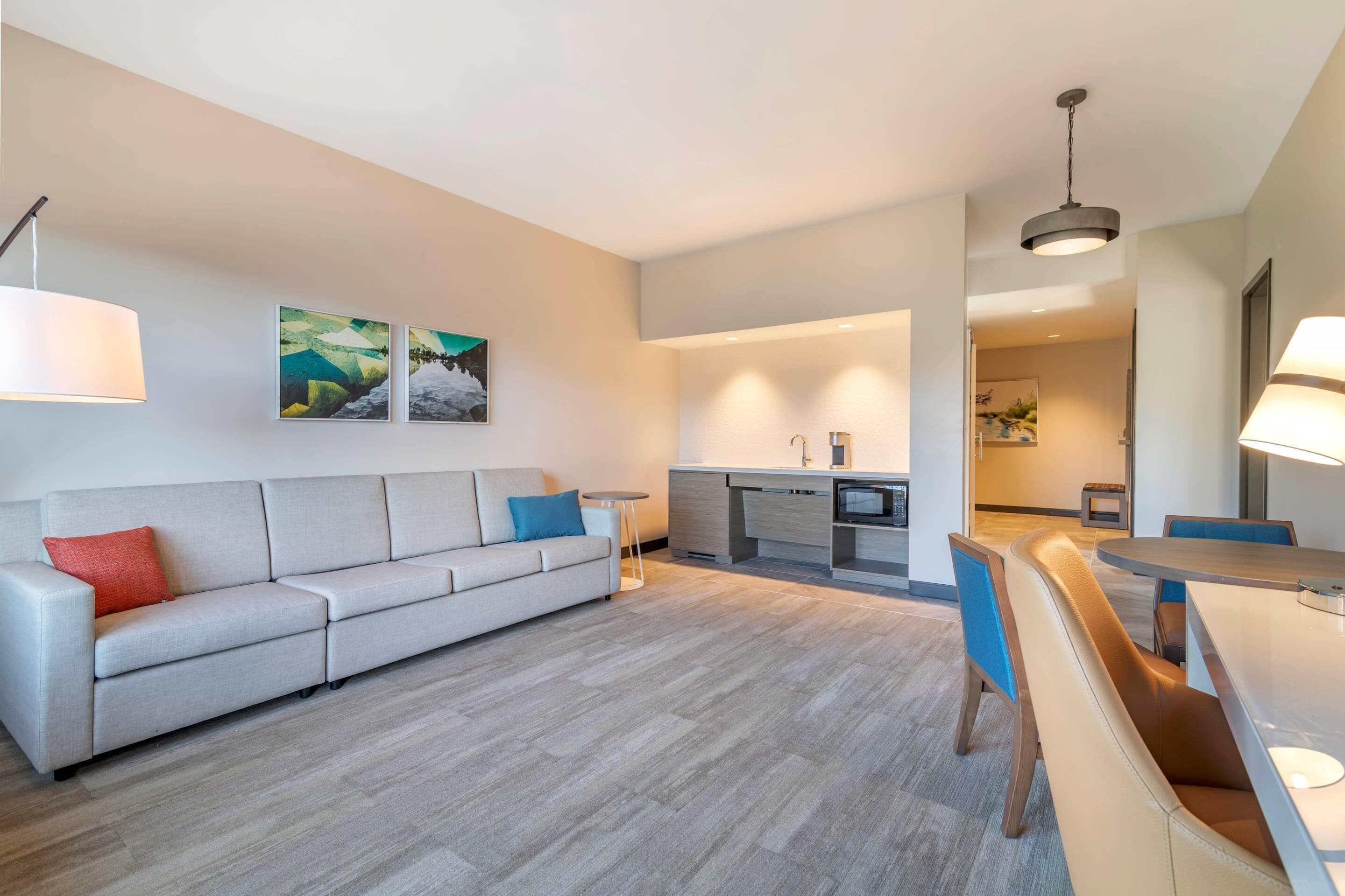 Una sala de estar moderna con un sofá, una mesa de comedor con sillas y una cocina al fondo.