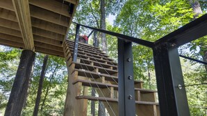 Una escalera de madera que sube a una plataforma en un área boscosa.