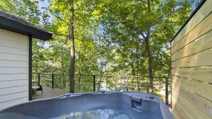 Un jacuzzi en una terraza de madera con vistas a árboles.