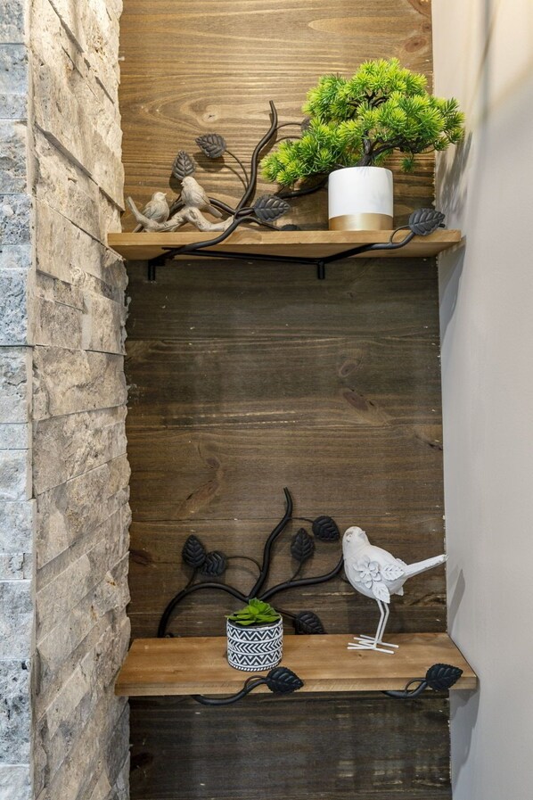 A wooden shelf with a small potted plant and decorative bird figures.