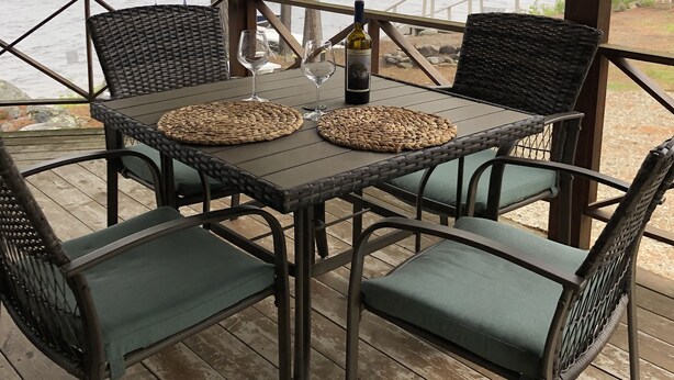 Un espace extérieur abrité, avec une table et des chaises, donnant sur un lac.