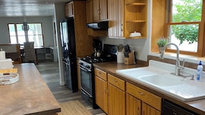 Une cuisine moderne avec des meubles en bois, un évier en acier inoxydable et une cuisinière intégrée.