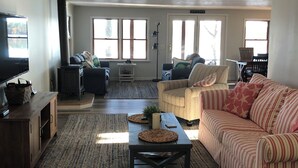Un salon spacieux doté d’une grande fenêtre, d’une cheminée, d’un canapé et d’une table basse.