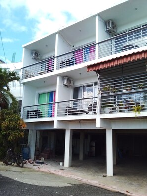A multi-story building with balconies, air conditioning units, and a covered entrance.