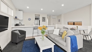 Ein modernes Wohnzimmer mit einem grauen Sofa, einem weißen Couchtisch und einem blauen Teppich.
