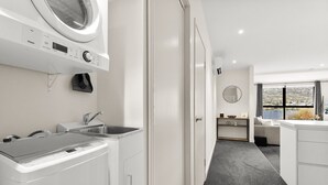 Une cuisine moderne équipée d’un lave-linge et d’un sèche-linge intégrés, d’un évier et offrant une vue sur un paysage magnifique grâce à une grande fenêtre.