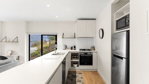 Une cuisine moderne dotée d’un grand îlot central, d’appareils électroménagers en acier inoxydable et offrant une vue sur un paysage montagneux grâce à une grande fenêtre.
