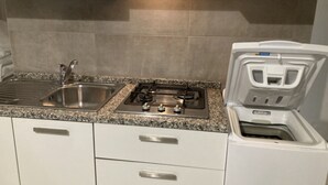 Una cocina con un lavamanos de acero inoxidable, una estufa a gas y un horno empotrado.