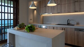 A modern kitchen with a central island, wooden cabinets, and pendant lighting. - Luxury Seaview Apartment, 1min Walk From Beach! (Apokoronas)