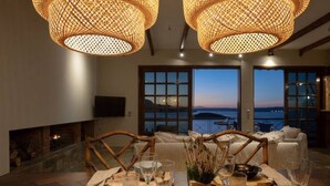 A dining area with a table set for four, a fireplace, and a view of the sea. - Luxury Seaview Apartment, 1min Walk From Beach! (Apokoronas)