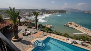 A poolside area with a view of the sea, lounge chairs, and a palm tree. - Luxury Seaview Apartment, 1min Walk From Beach! (Apokoronas)