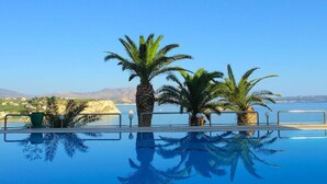 A swimming pool with palm trees and a view of the sea. - Coco Seaview Apartment, 60sec Walk From Beach! (Apokoronas)
