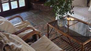 A cozy living room with wicker furniture, a fireplace, and a view through a large window. - Coco Seaview Apartment, 60sec Walk From Beach! (Apokoronas)